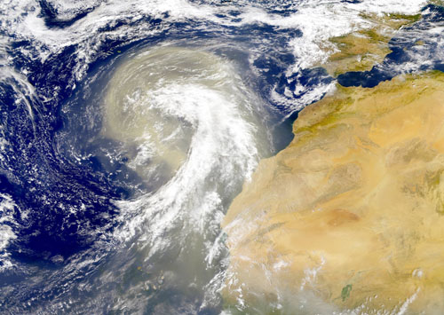 Imagen de satélite de una gran masa de polvo desplazándose hacia el oeste sobre las Islas Canarias, con un tamaño equivalente al de la península Ibérica (margen superior derecho). Imagen: NASA Earth Observatory / CSIC
